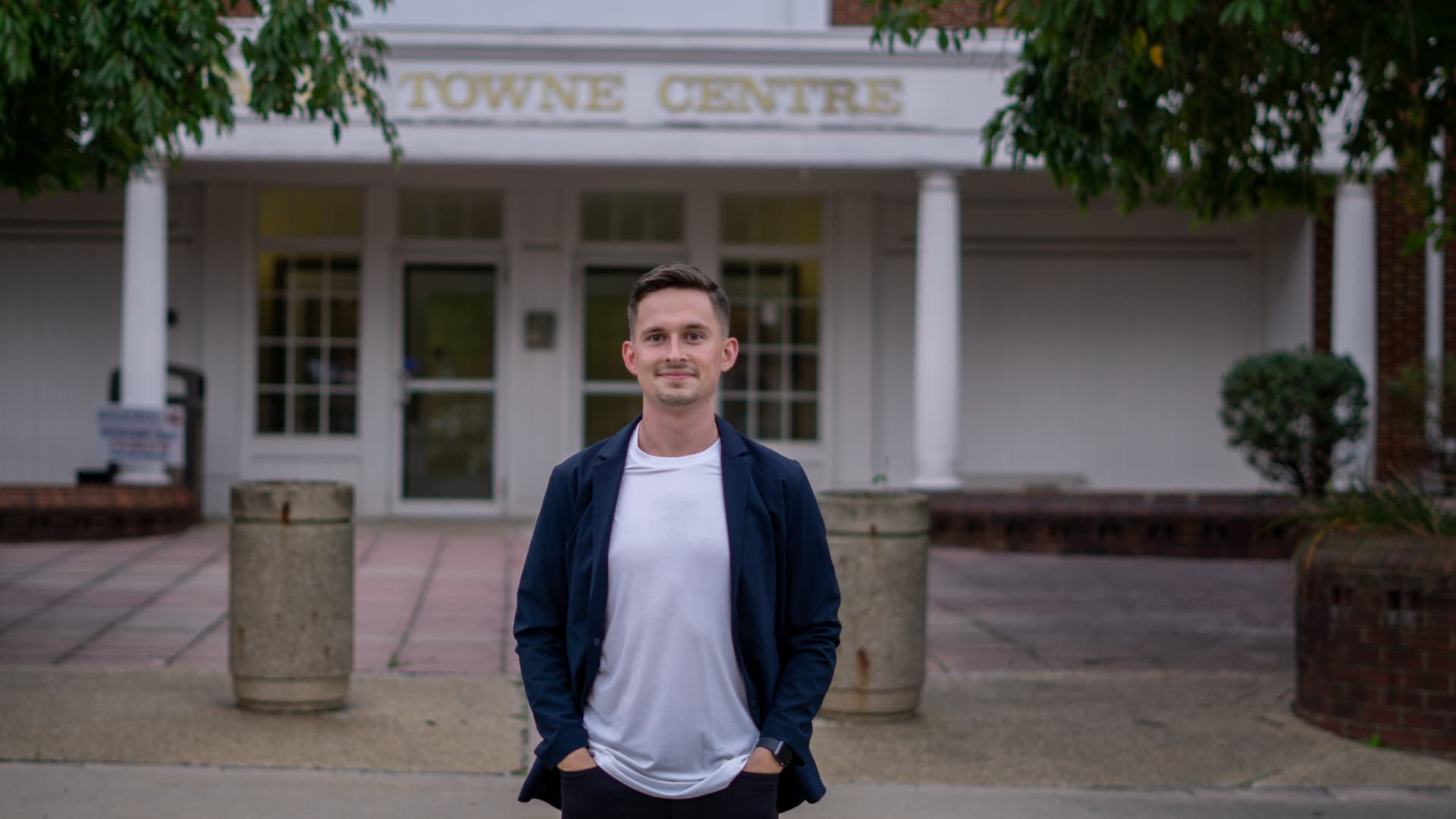 Justin Mancari in a navy blazer outside a neighborhood town centre